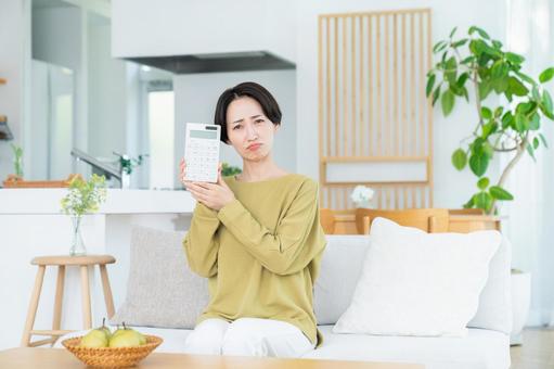 リビングで電卓を持つミドルの女性 リビングで電卓を持つミドルの女性の写真