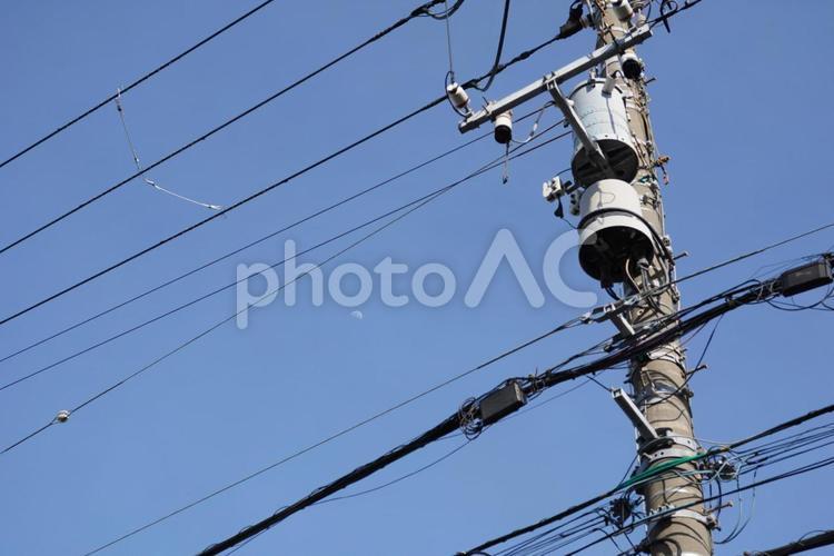 電線越しの白い月 電柱,蒼天,空の素材の写真素材