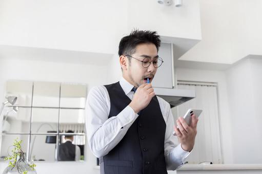 出勤前に歯磨きをしながらスマホを見る男性 ビジネスマン,男性,歯ブラシの写真素材