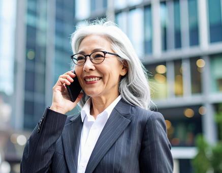 街中で電話をかけるシニアの女性の写真