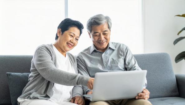 リビングで仲良くパソコンを見るシニア夫婦 リビングで仲良くパソコンを見るシニア夫婦の写真