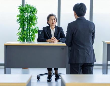 女性上司とその前に立つサラリーマンの部下の写真