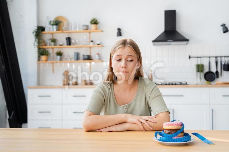 メジャーを巻いたドーナツを見る女性 女性,人物,見るの写真素材