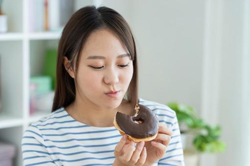 ドーナツを食べる若い女性 ドーナツを食べる若い女性 ドーナツ,スイーツ,ダイエットの写真素材