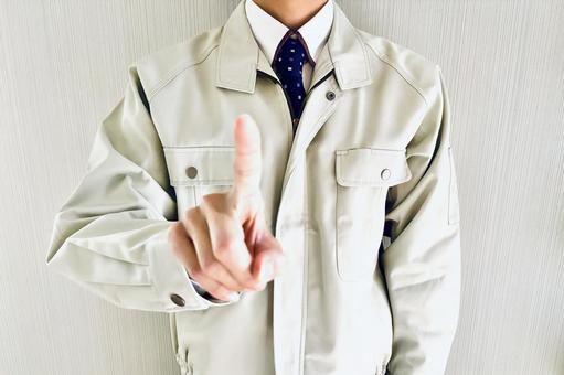 人差し指を立てる作業着姿の男性 ポイント,指す,ここの写真素材
