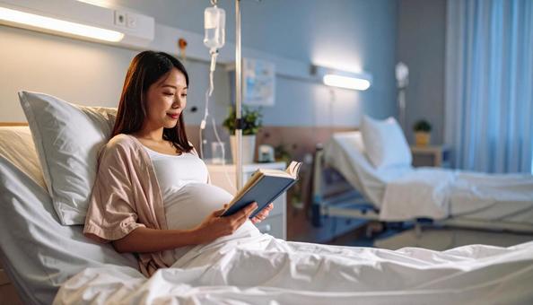 本を読んで安静にして点滴を打つ妊婦 本を読んで安静にして点滴を打つ妊婦の写真