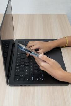 ノートPCとスマホで作業する手元 作業,パソコン,スマートフォンの写真素材