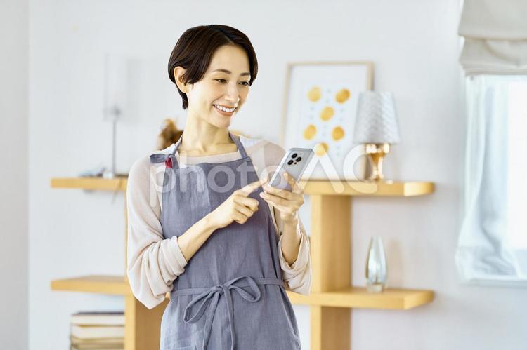 スマホを使う主婦　エプロン　女性 スマホ,主婦,エプロンの写真素材