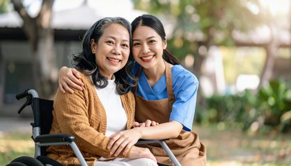 笑顔の若い介護士と車いすのシニア女性の写真