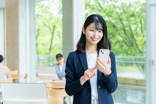 オフィスでスマホを使うビジネスウーマン オフィスでスマホを使うビジネスウーマン ビジネスウーマン,スマホ,笑顔の写真素材