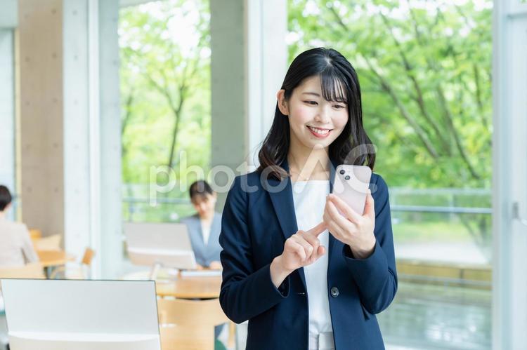 オフィスでスマホを使うビジネスウーマン ビジネスウーマン,スマホ,笑顔の写真素材
