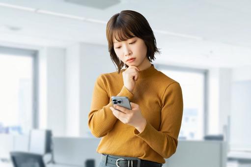 スマホを見て考える女性・ビジネスウーマン 女性,困る,考えるの写真素材