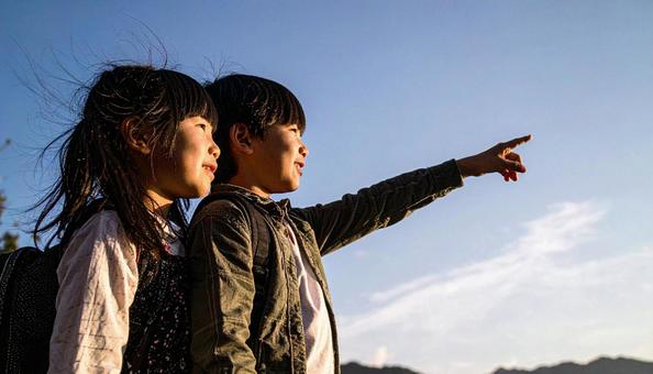 夕焼けの空を見つめる日本人の少年 夕焼けの空を見つめる日本人の少年の写真