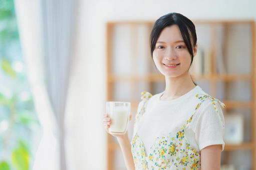 カメラ目線で牛乳の入ったコップを持つ女性の写真