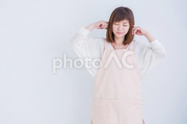 耳をおさえるエプロン姿の女性 うるさい,女性,エプロンの写真素材