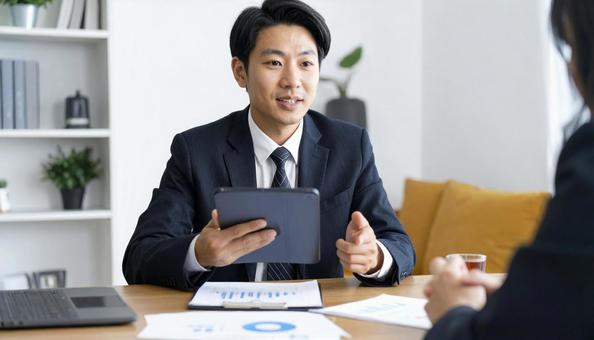 タブレットを使って説明する男性営業マン タブレットを使って説明する男性営業マンの写真