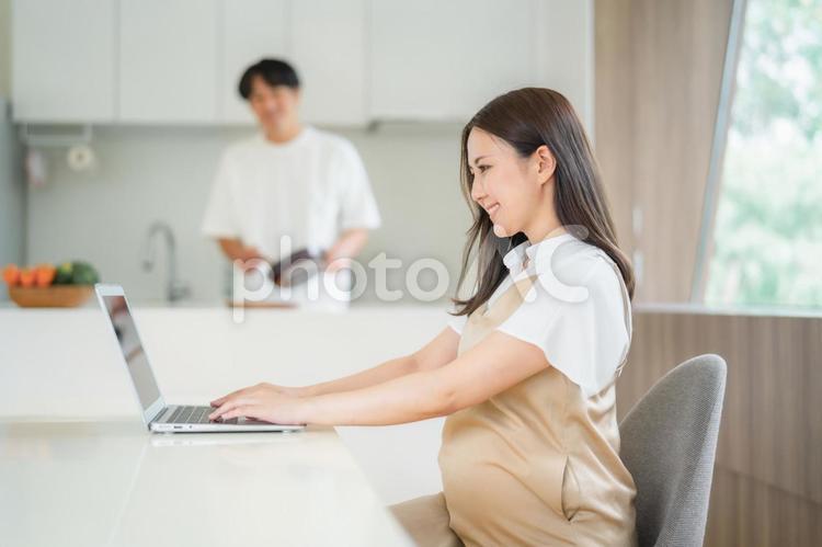 テレワークする妊婦と家事をする男性 テレワーク,妊婦,妊娠の写真素材