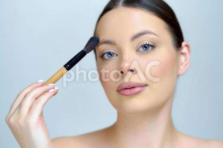 メイクブラシを顔に当たる女性 女性,ブラシ,メイクブラシの写真素材