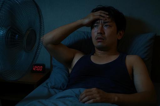 熱帯夜に寝苦しそうな男性 熱帯夜に寝苦しそうな男性の写真
