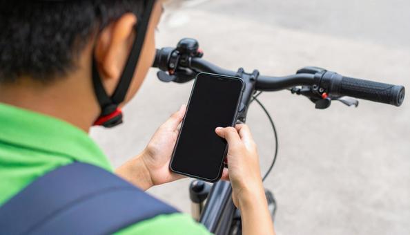 自転車を止めてスマホを見る男の子 自転車を止めてスマホを見る男の子の写真