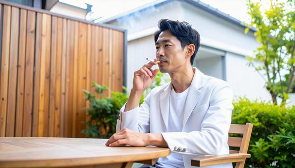 家の外でタバコを吸う日本人男性 家の外でタバコを吸う日本人男性の写真
