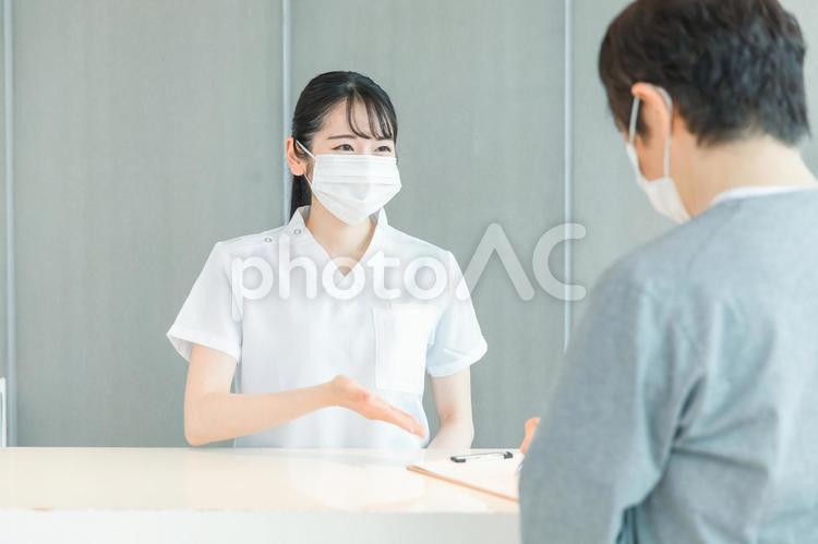 受付にいる看護師と患者（マスク） 医療事務,マスク,受付の写真素材