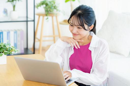 自宅でノートパソコンを操作する若い女性 若い女性,ノートパソコン,笑顔の写真素材