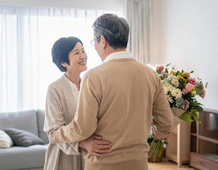 記念日に花束を贈る夫のシニア夫婦の写真