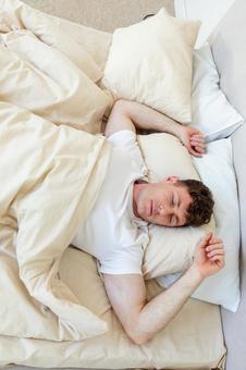 ベッドで仰向けで寝ている男性 縦,男性,外国人の写真素材