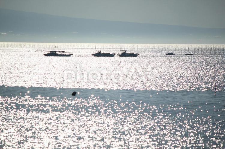 キラキラ光る海に漁船がゆらゆら通る シルエット,漁船,光の写真素材