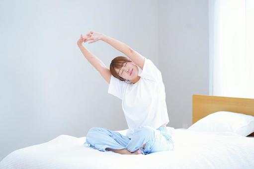 ベッドに座りストレッチ中の女性の写真
