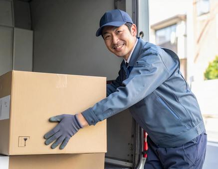 トラックから荷物を出す宅配男性ドライバー トラックから荷物を出す宅配男性ドライバーの写真