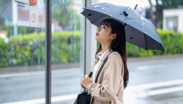 雨の中バス停でバスを待つ日本人女性 雨の中バス停でバスを待つ日本人女性の写真