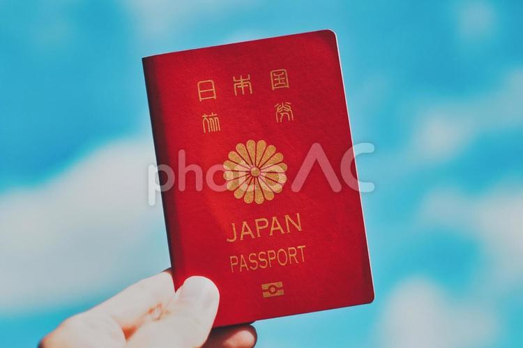 パスポートを持つ人の手元と青空背景 パスポート,旅券,旅行の写真素材