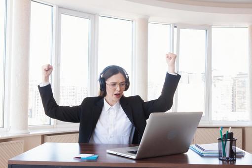 パソコンを見ながら両手を上げ喜ぶ女性 女性,外国人,ガッツポーズの写真素材