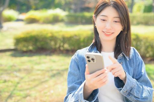 スマホを指差す女性 スマホを指差す女性の写真