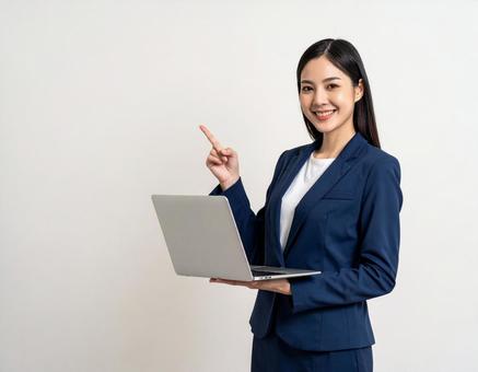 ノートパソコンを持ち案内する会社員女性 ノートパソコンを持ち案内する会社員女性の写真