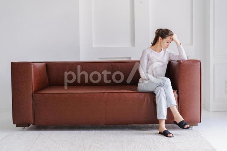 ソファで額を押さえる女性 女性,外国人,欧米人の写真素材
