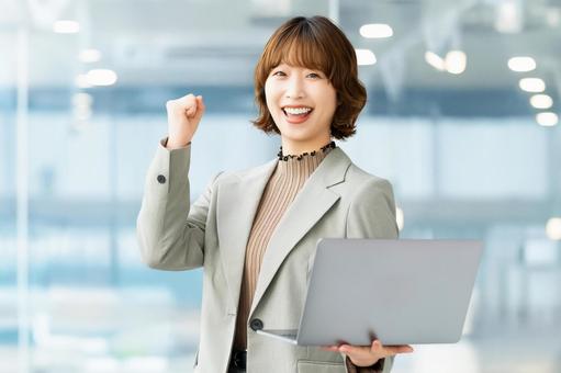 パソコンを持ってガッツポーズをする女性 女性,ビジネス,笑顔の写真素材