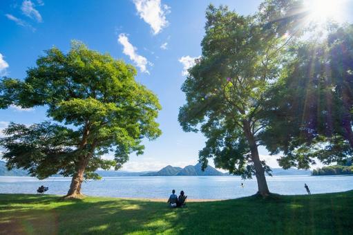 人々が木陰で憩う、初秋の洞爺湖畔 人々が木陰で憩う、初秋の洞爺湖畔 洞爺湖,湖畔,水辺の写真素材