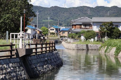 川のある住宅街の町並みと山と空の風景 川のある住宅街の町並みと山と空の風景の写真