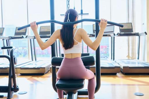 スポーツジムで筋トレする女性の後ろ姿 スポーツジム,筋トレ,女性の写真素材