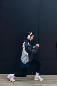 黒い壁の前で準備運動する女性 黒い壁の前で準備運動する女性 女性,ヘッドフォン,人物の写真素材