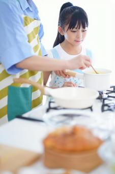 親子で鍋を見つめる料理中の様子の写真