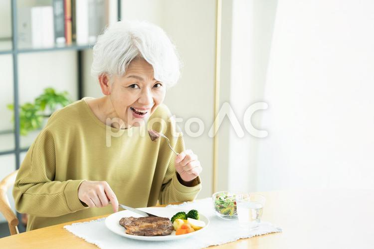 ステーキを食べるシニアの女性 ステーキ,食事,肉の写真素材