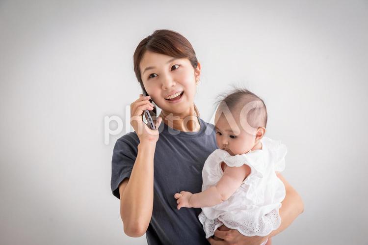 赤ちゃんを抱っこして電話するママ 赤ちゃん,抱っこ,ママの写真素材