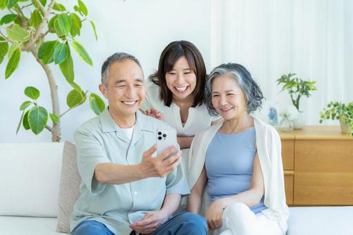 リビングでスマホを見るシニア夫婦と子供 シニア,夫婦,スマホの写真素材