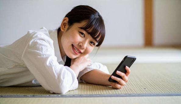畳でスマホ見る女性 畳でスマホ見る女性の写真