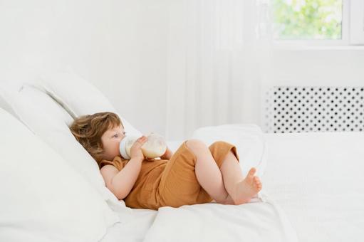 ベッドで哺乳瓶を持ち1人で飲んでいる赤ちゃん ベッドで哺乳瓶を持ち1人で飲んでいる赤ちゃん 赤ちゃん,哺乳瓶,ミルクの写真素材