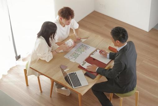 営業マンと家づくりの相談をする若い夫婦 営業マンと家づくりの相談をする若い夫婦 住宅,家,新築の写真素材